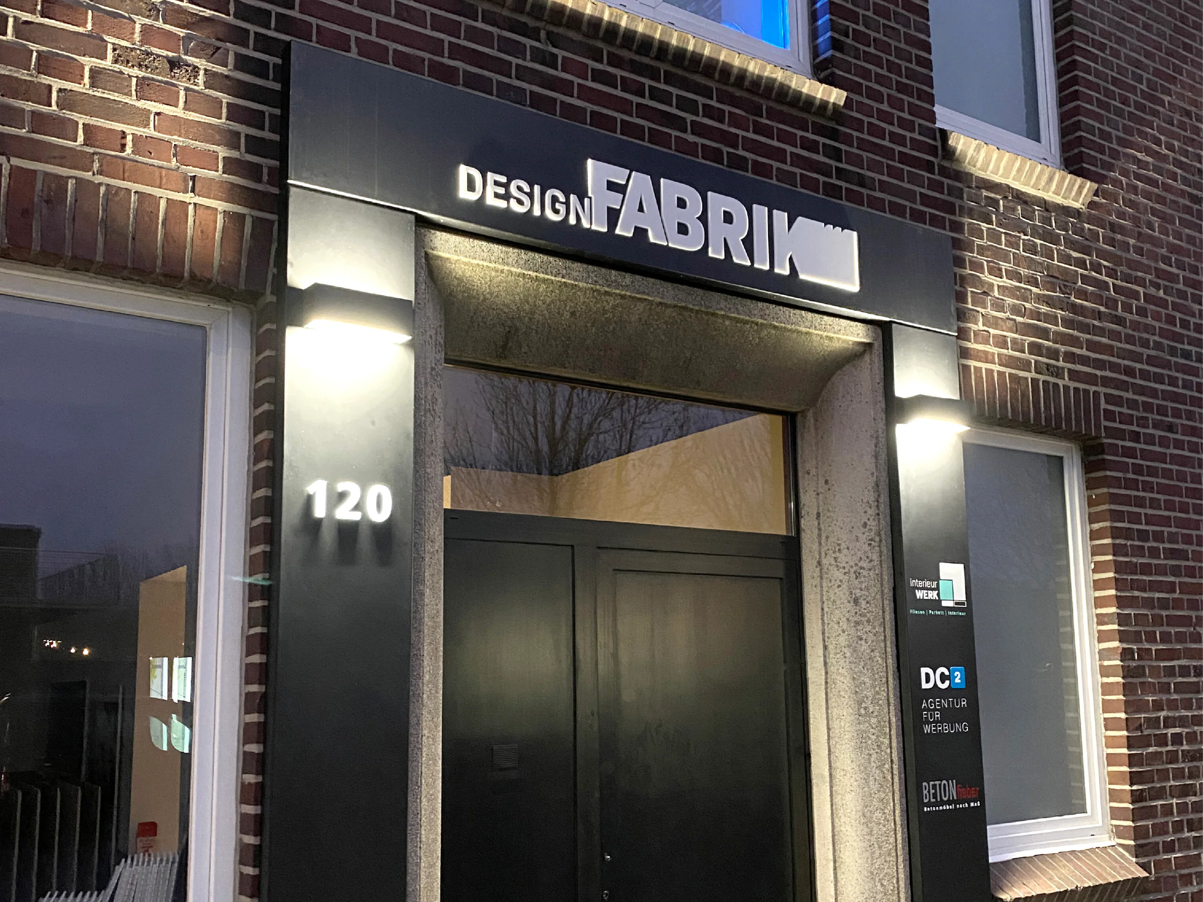 Leuchtende Eingangsbeschriftung von Designfabrik an der Fassade
